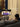 Person watching a basketball game on a portable TV stand in a living room.